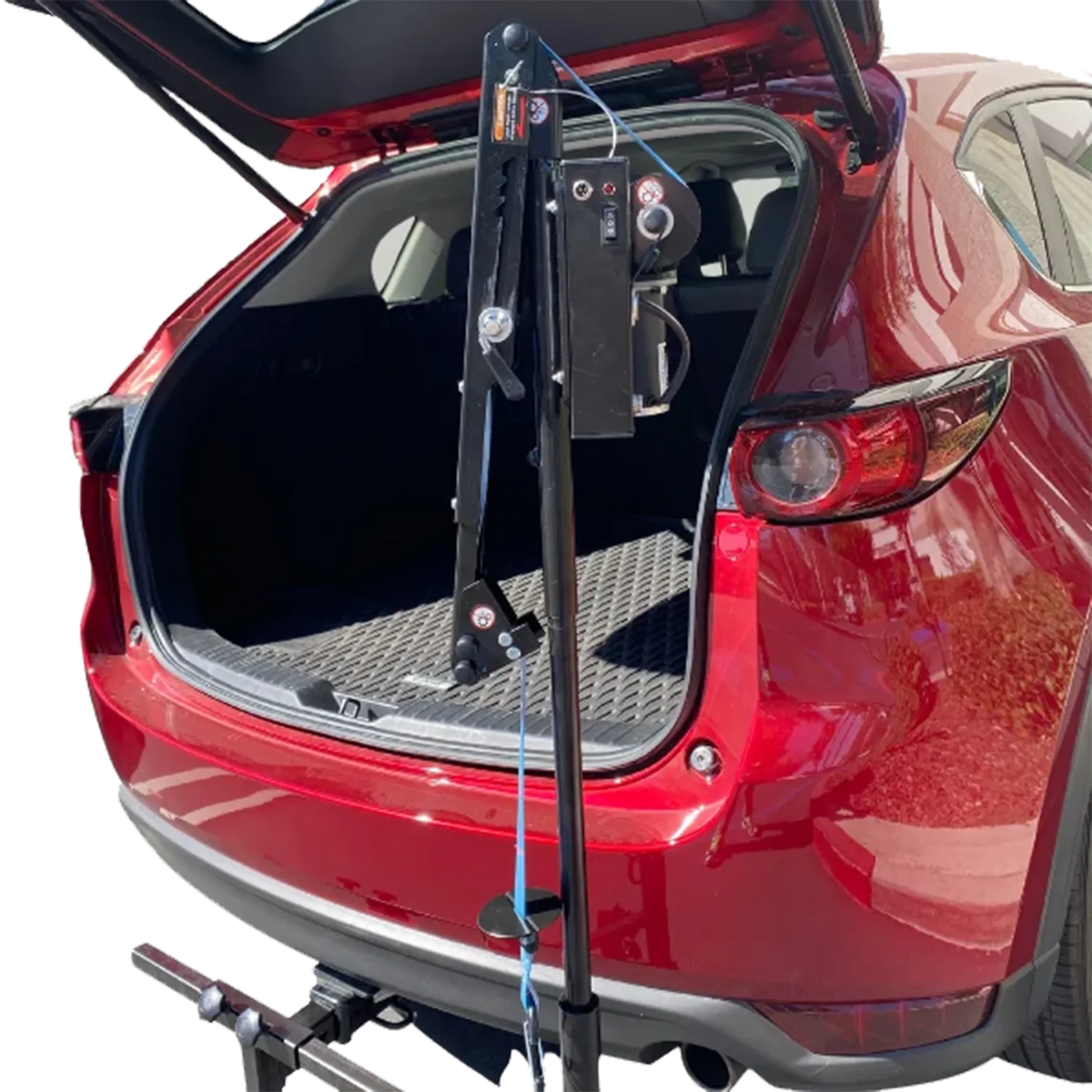 A black car hitch towing package with a winch and mounting bracket shown installed in front of the open trunk of a red SUV, isolated on a white background.